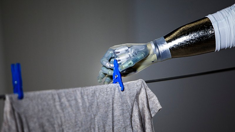 Roboterhand befestigt ein T-Shirt mit einer Wäscheklammer an der Leine | Bild: picture alliance / AMELIE-BENOIST Roboterhand befestigt ein T-Shirt mit einer Wäscheklammer an der Leine