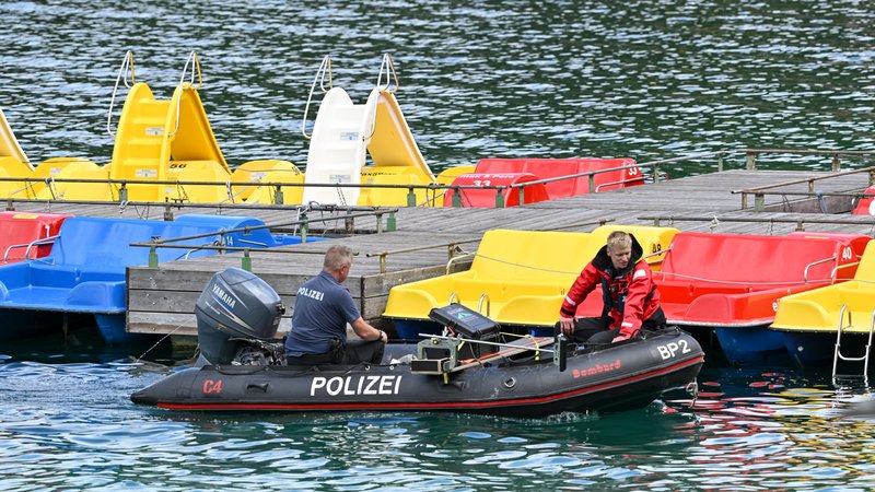Polizeitaucher fahren in einem Schlauchboot vor den Tretbooten eines geschlossenen Bootsverleihs auf den Eibsee. | Bild: pa/dpa/Peter Kneffel Polizeitaucher fahren in einem Schlauchboot vor den Tretbooten eines geschlossenen Bootsverleihs auf den Eibsee.