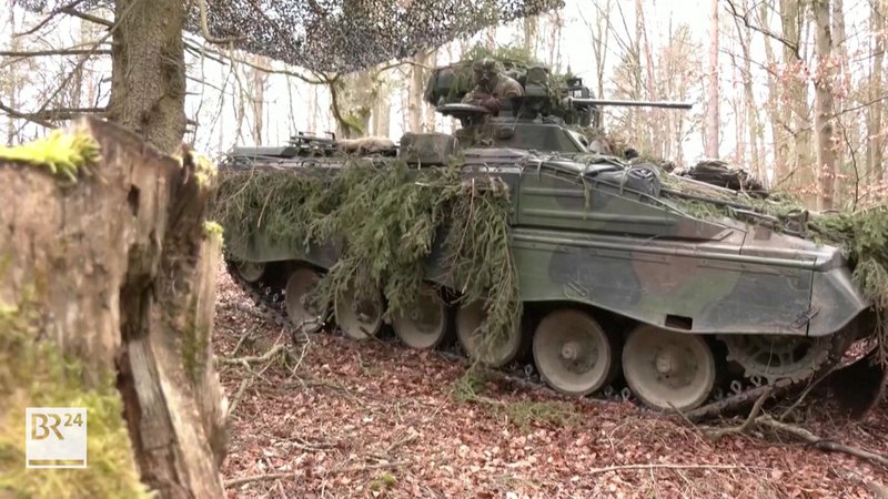 Ein Panzer der Bundeswehr fährt durch einen Wald.