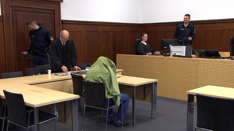 Angeklagter versteckt sich in Gerichtssaal unter seiner Jacke.