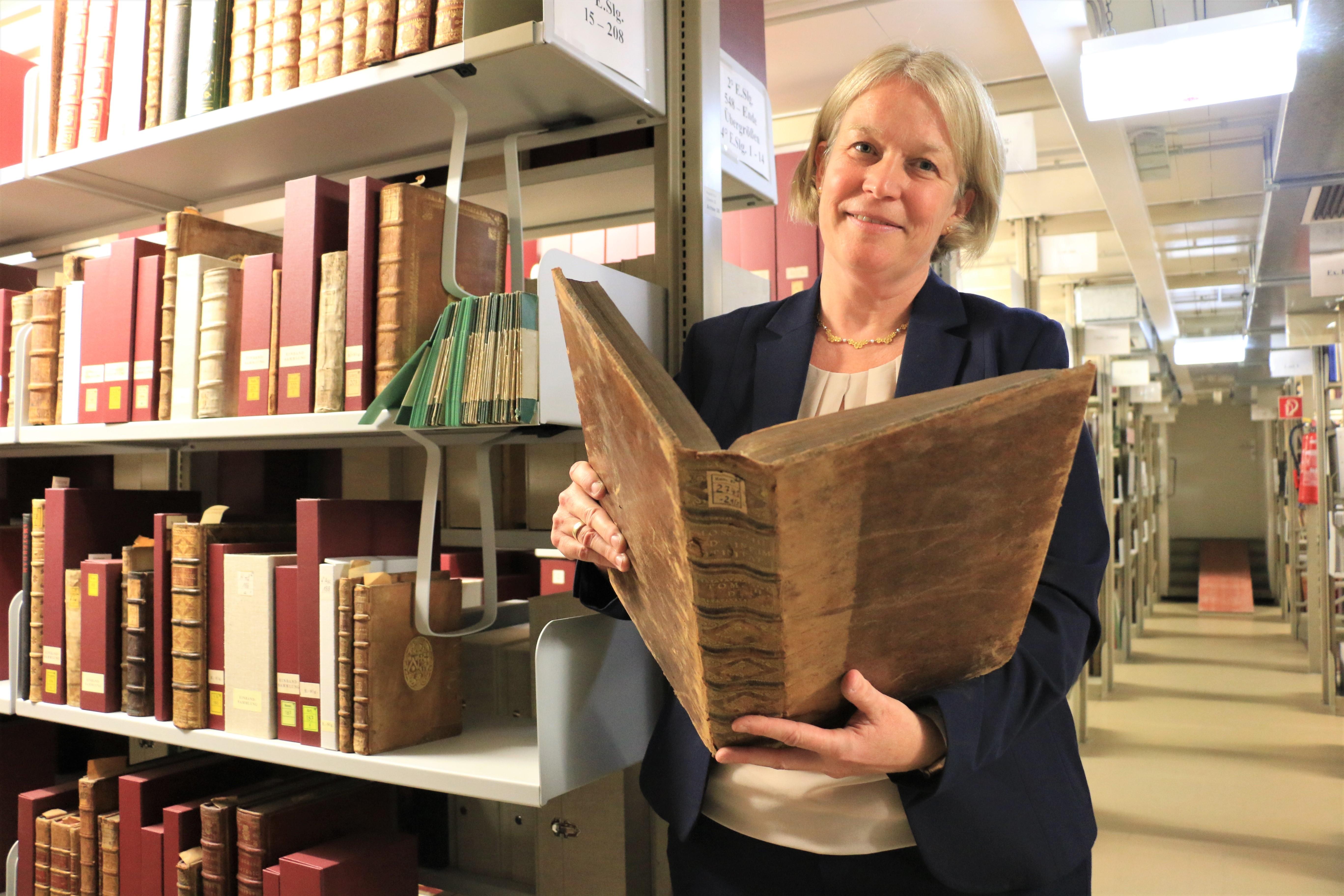 Die Expertin hält einen alten Band in den Händen