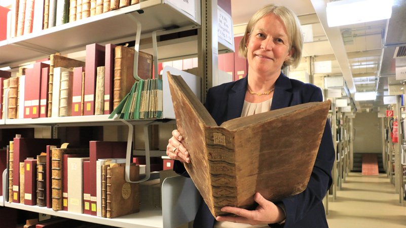 Die Expertin hält einen alten Band in den Händen | Bild: Jungblut/BR Die Expertin hält einen alten Band in den Händen
