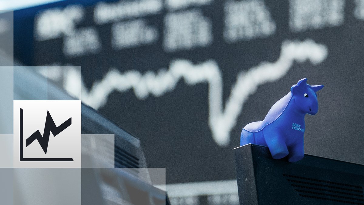 ein blauer Stier aus Gummi sitzt auf der oberen Kante eines Bildschirmes, im Hintergrund die Kurstafel der Börse
