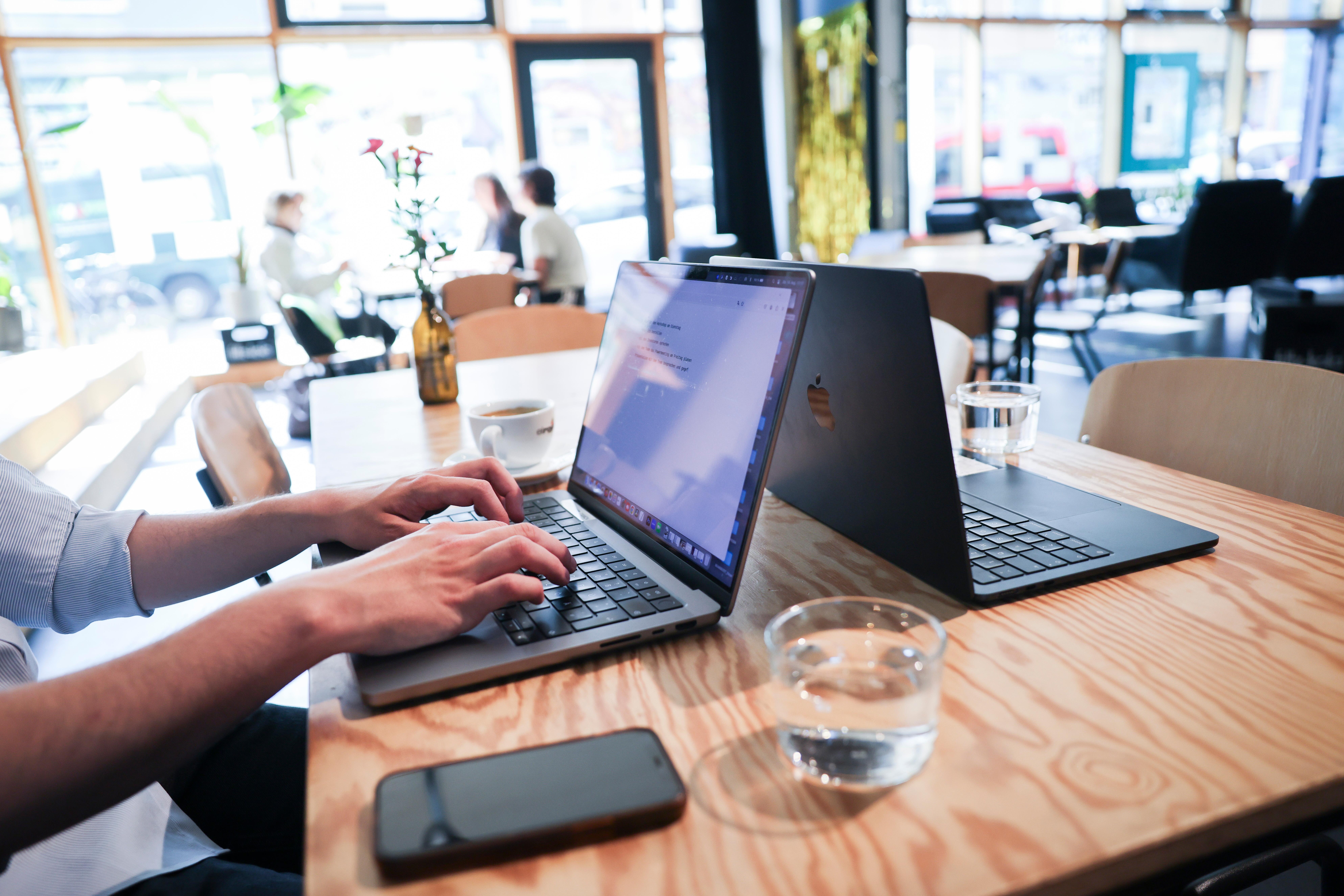 Ein Mensch arbeitet an seinem Computer an einem Arbeitsplatz im Coworking-Space