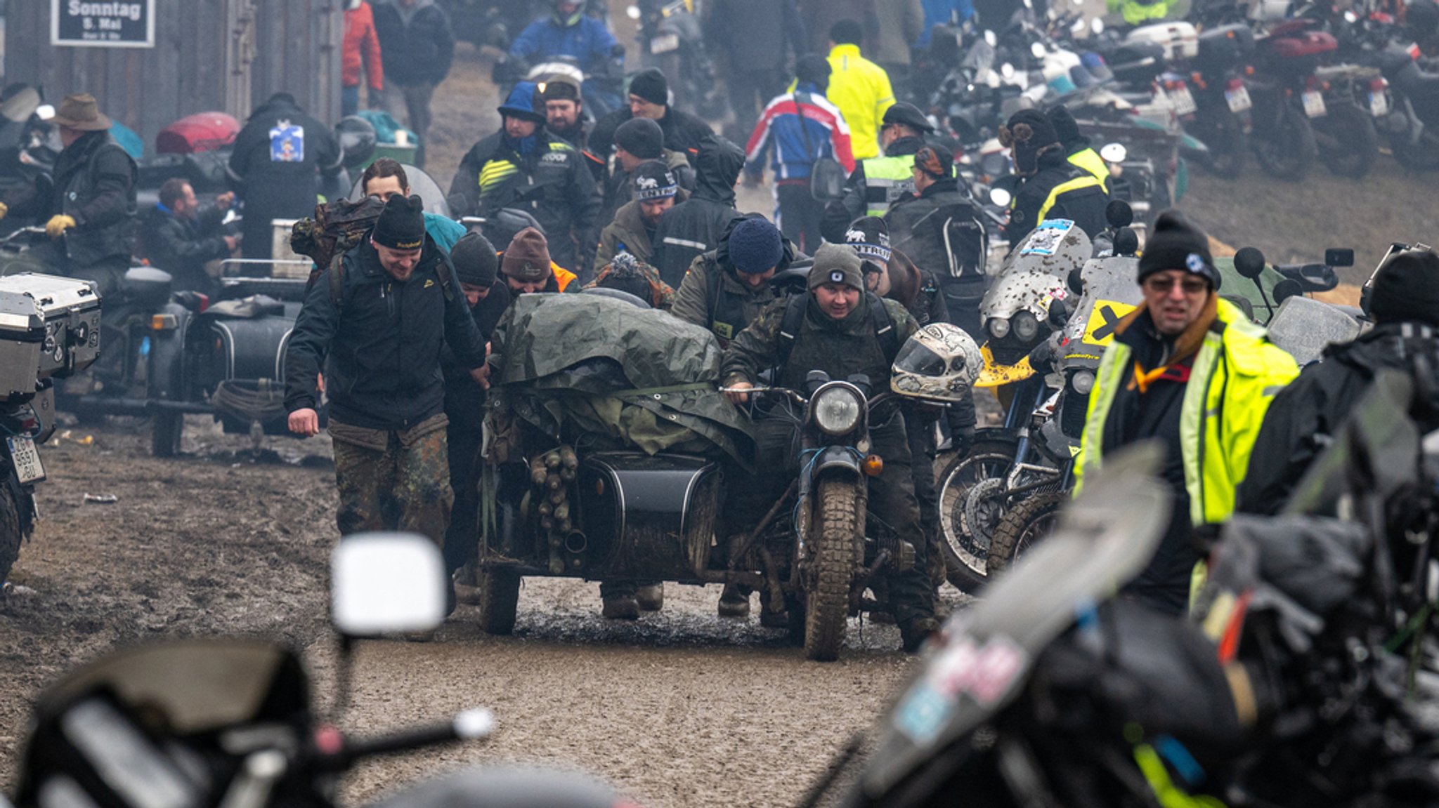 Personen mit Motorrädern, schlammiger Untergrund