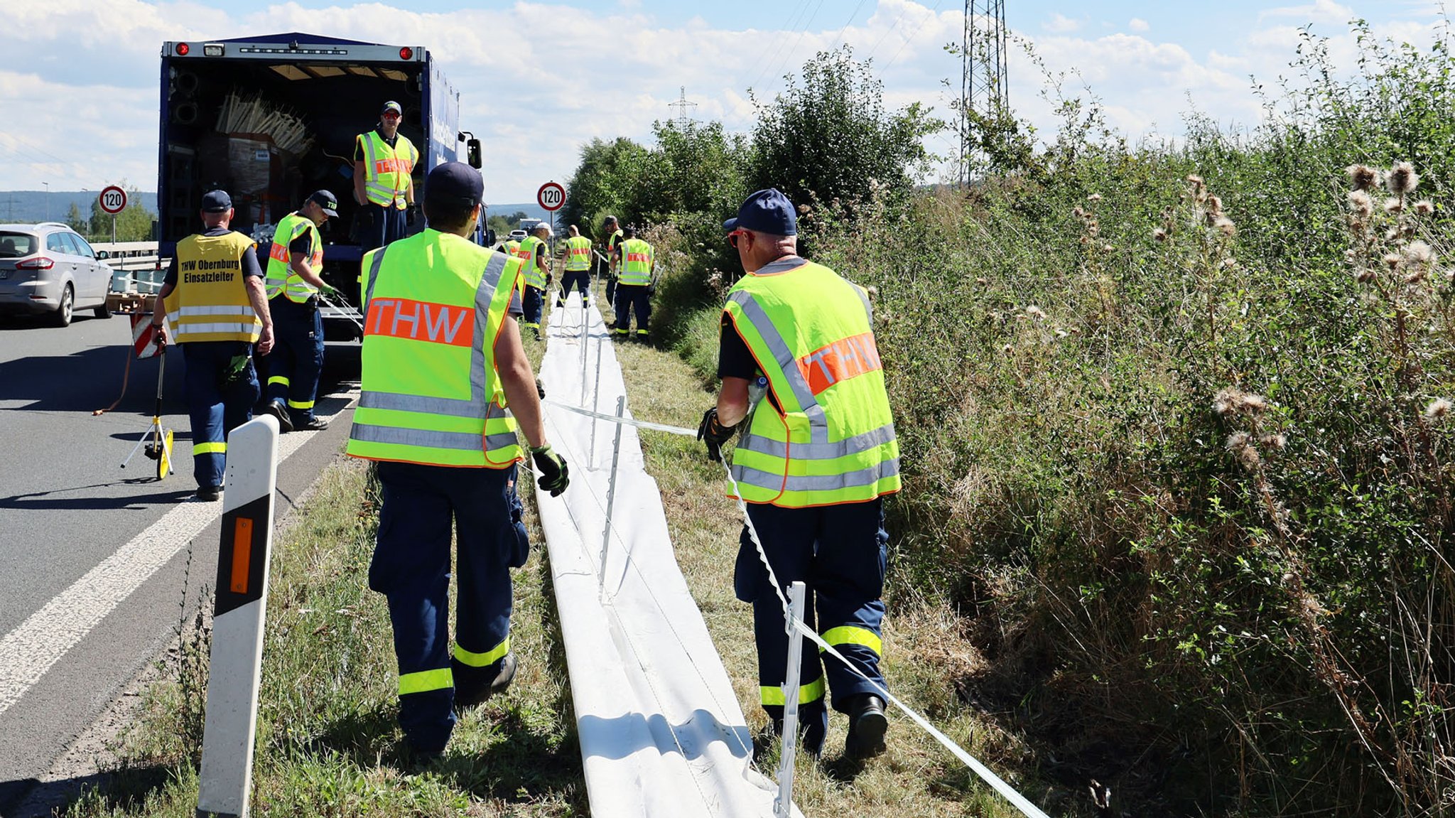 THW-Helfer errichten einen Elektrozaun an der B469, um infizierte Wildscheine aufzuhalten.