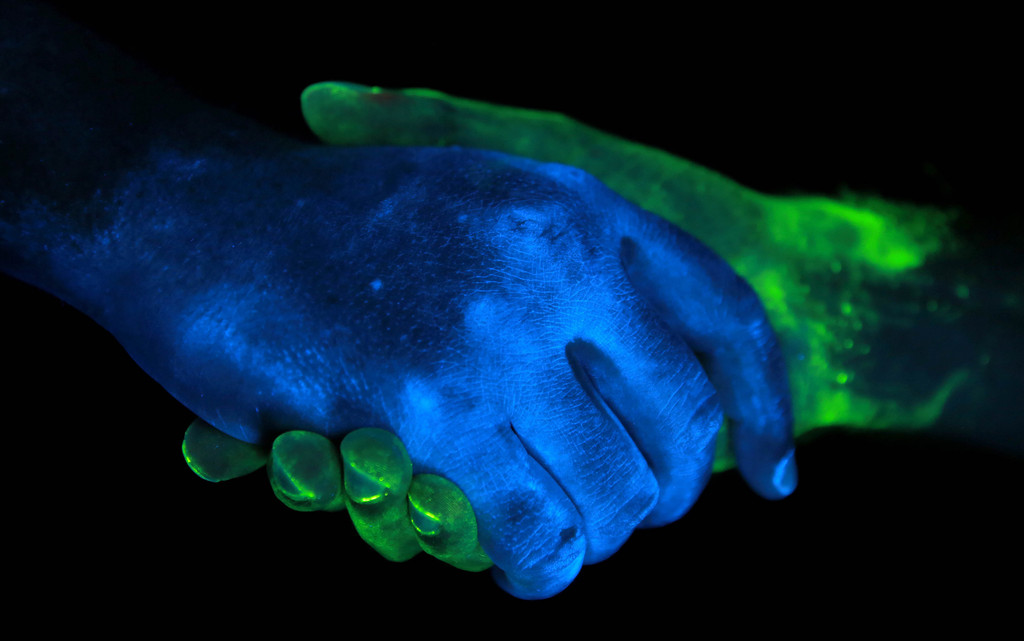 Handshake von zwei Händen im ultravioletten Licht.