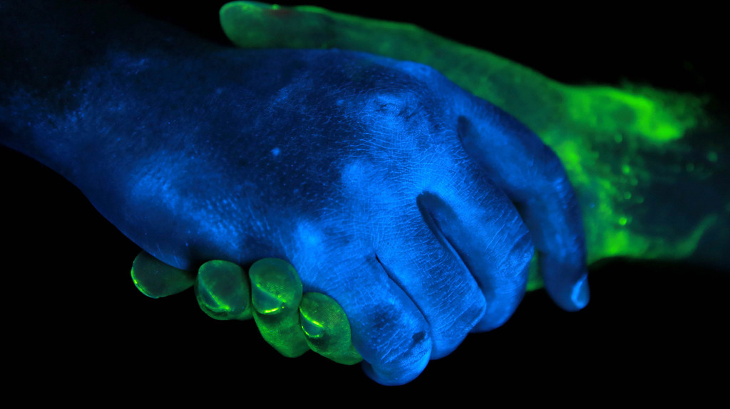 Handshake von zwei Händen im ultravioletten Licht.