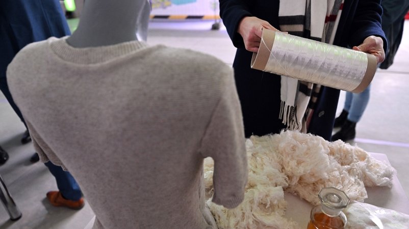 Eine Besucherin betrachtet Fasern aus Baumwolltextil-Recycling während der Einweihung des Demonstration and Innovation Center for Textile Circular Economy. | Bild: dpa-Bildfunk/Martin Schutt Eine Besucherin betrachtet Fasern aus Baumwolltextil-Recycling während der Einweihung des Demonstration and Innovation Center for Textile Circular Economy.