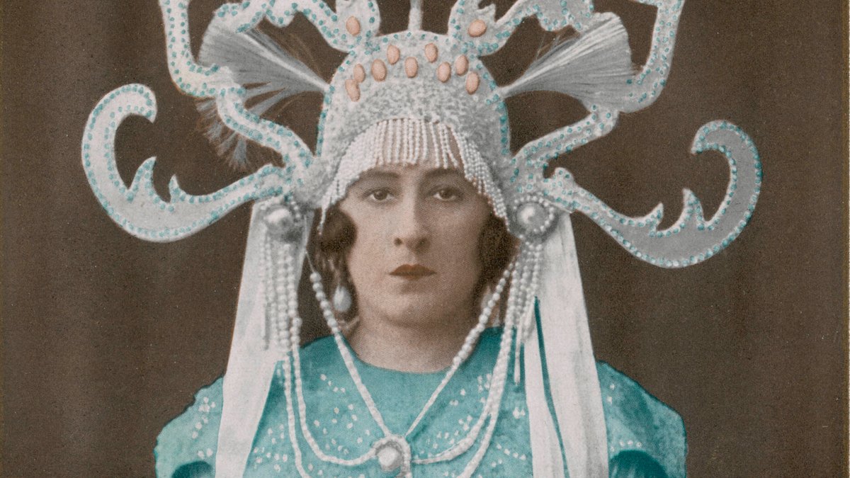 Die Sängerin in einem türkisen Kleid mit ausladendem Kopfschmuck