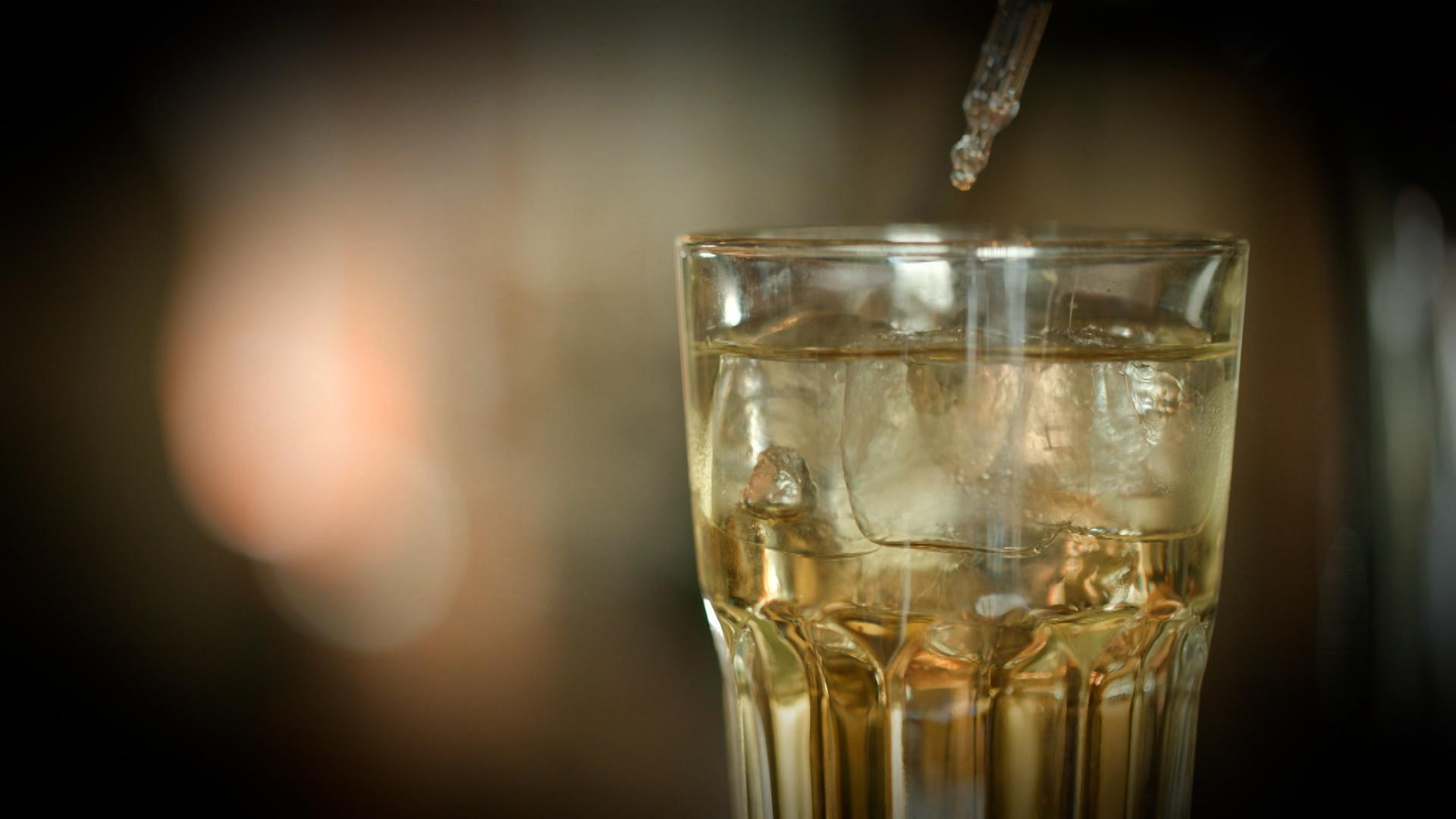 Mit einer Pipette wird eine Flüssigkeit in ein Trinkglas gegeben