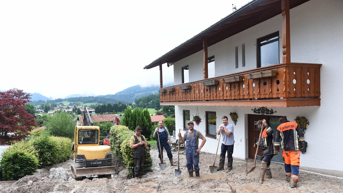 Helfer räumen den Schlamm durch Unwetter und Hochwasser in Bayern im Berchtesgadener Land weg