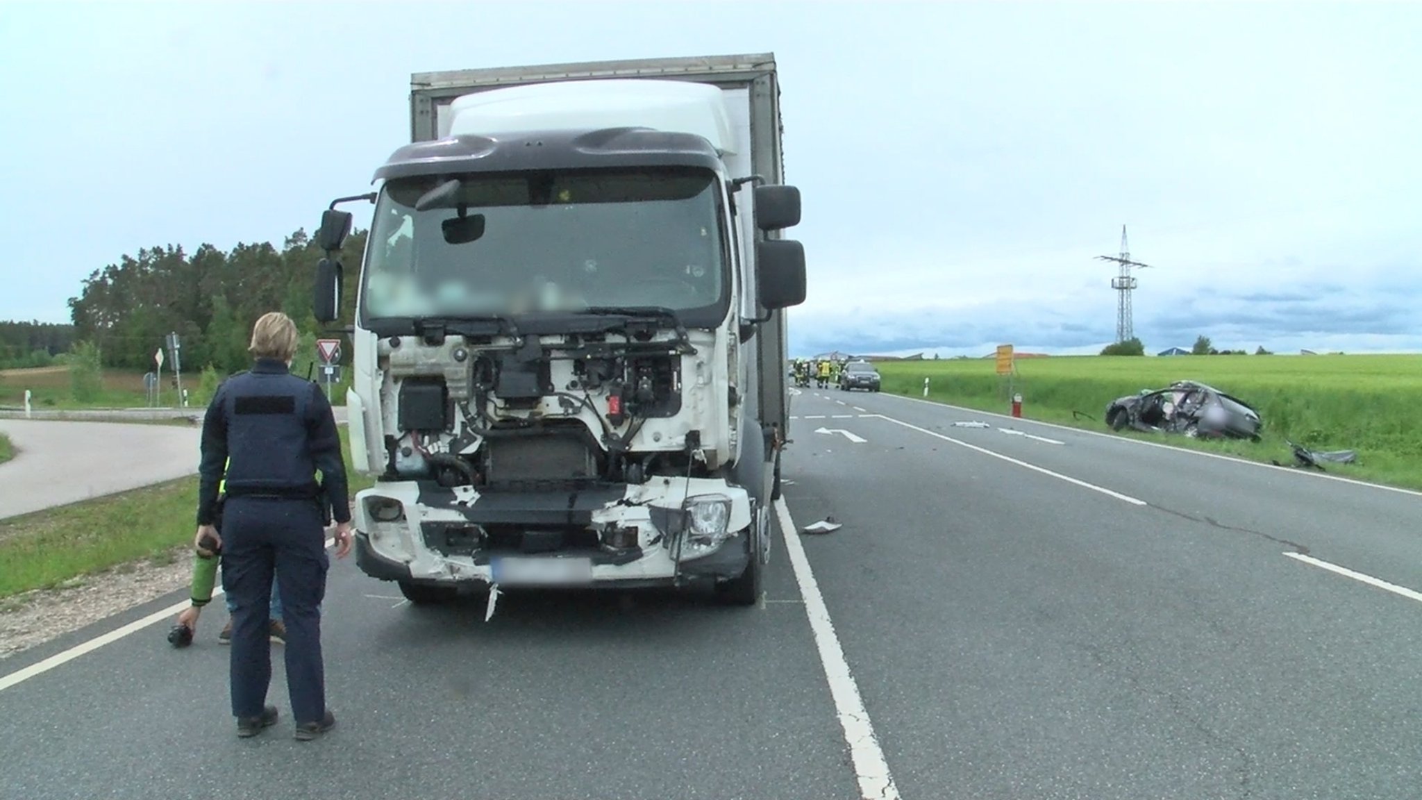 Ein Polizist vor einem Lkw mit kaputter Front auf der B14.