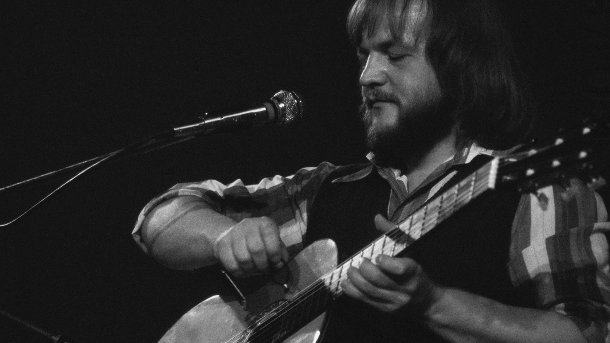 Mann mit Siebziger-Jahre-Frisur und Gitarre