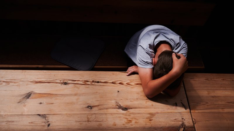 Ein Jugendlicher versteckt sein Gesicht unter seinen Armen und liegt mit dem Kopf auf einem Tisch (gestellte Szene) (Archiv- und Symbolbild) | Bild: picture alliance/dpa|Annette Riedl Ein Jugendlicher versteckt sein Gesicht unter seinen Armen und liegt mit dem Kopf auf einem Tisch (gestellte Szene) (Archiv- und Symbolbild)