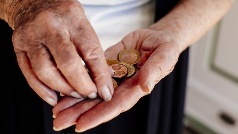 Hände einer älteren Person, darin verschiedene Münzen