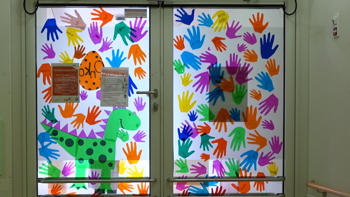 Eine Tür zur Regensburger Kinderonkologie ist geschmückt mit bunten Abdrücken von Kinderhänden.