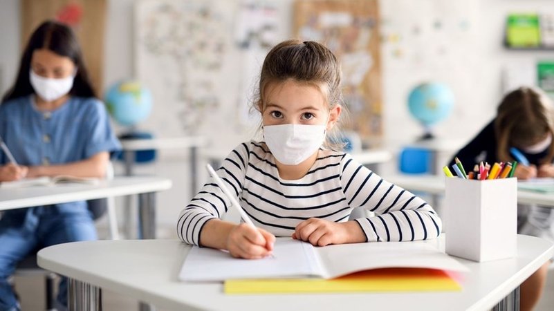 Ein Schulkind mit Maske im Unterricht. Strenge Hygieneregeln helfen bei der Corona-Pandemie.