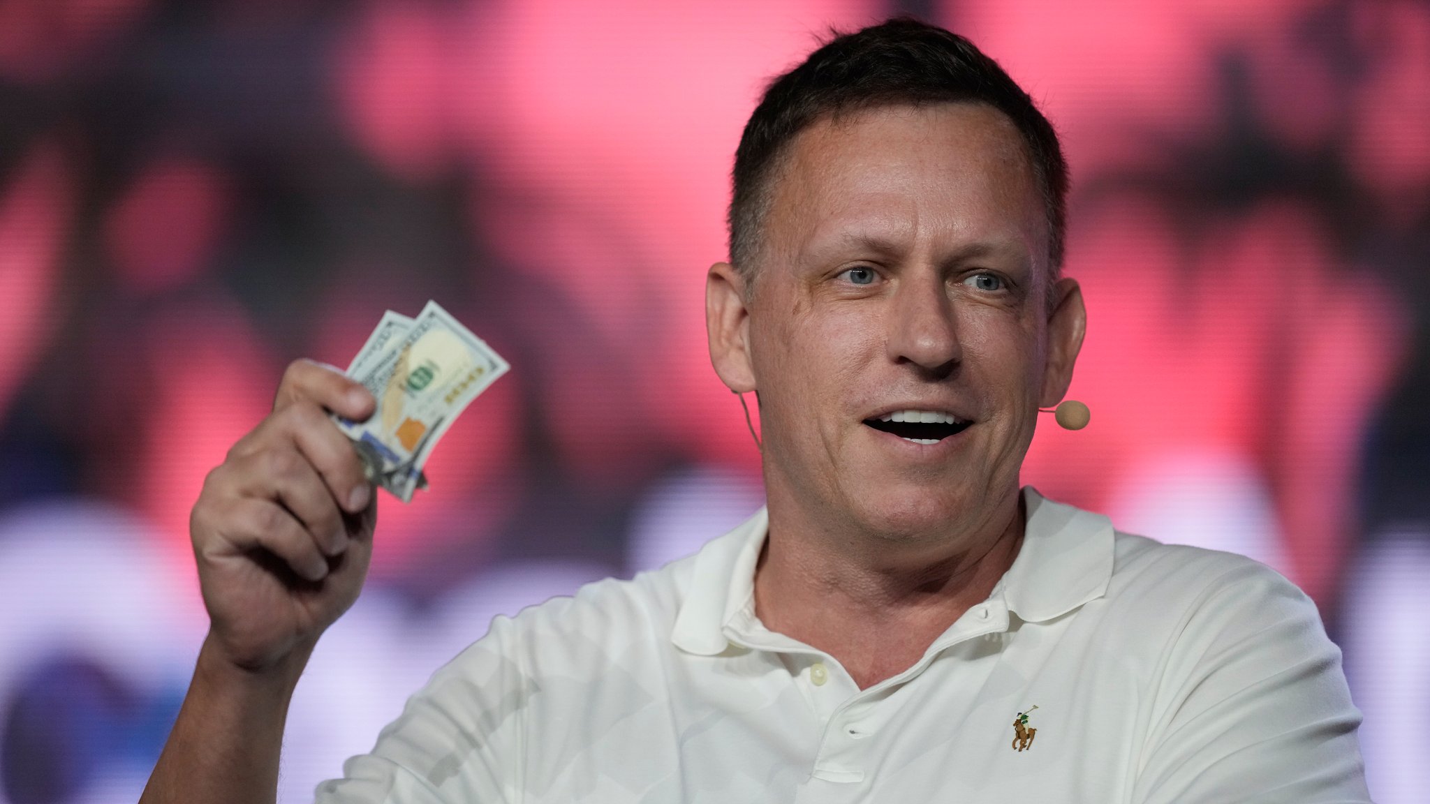 Peter Thiel, Mitbegründer von PayPal und Palantir, überreicht den Teilnehmern während einer Grundsatzrede auf der Bitcoin-Konferenz zwei Hundert-Dollar-Scheine. | Bild: picture alliance / ASSOCIATED PRESS | Rebecca Blackwell Peter Thiel, Mitbegründer von PayPal und Palantir, überreicht den Teilnehmern während einer Grundsatzrede auf der Bitcoin-Konferenz zwei Hundert-Dollar-Scheine.