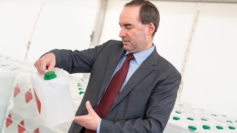Hubert Aiwanger, Wirtschaftsminister und Landesvorsitzender der Freien Wähler in Bayern, betrachtet in einer Zeltstadt für Desinfektionsmittel einen Kanister mit Handdesinfektionsmittel. 