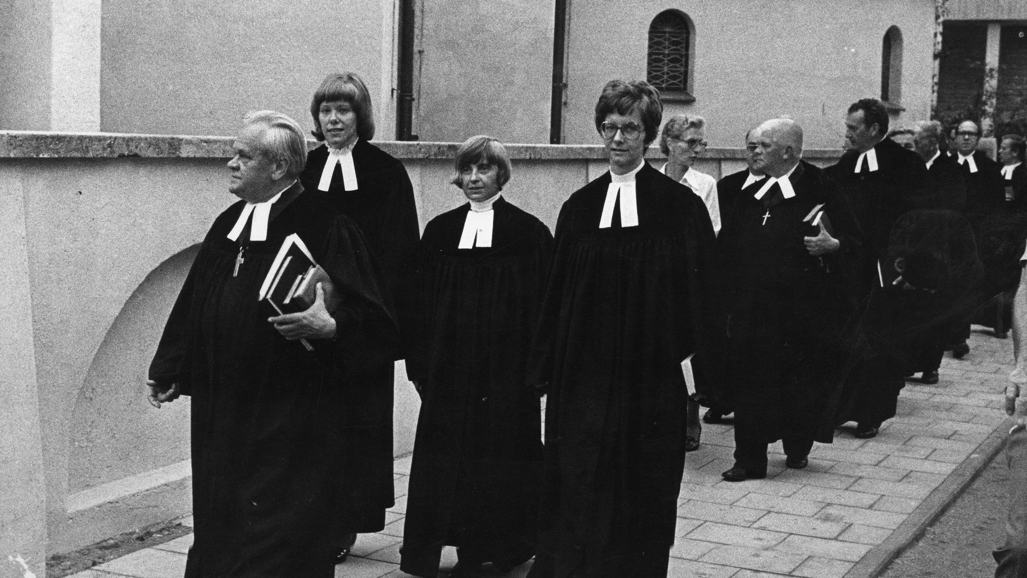 Drei evangelische Pfarrerinnen laufen hinter einem Pfarrer. Sie sind die ersten in Bayern.