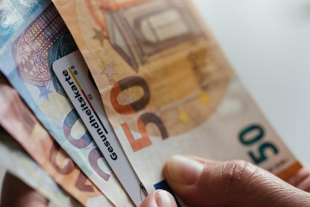Eine Krankenkassen-Chipkarte zwischen Geldscheinen