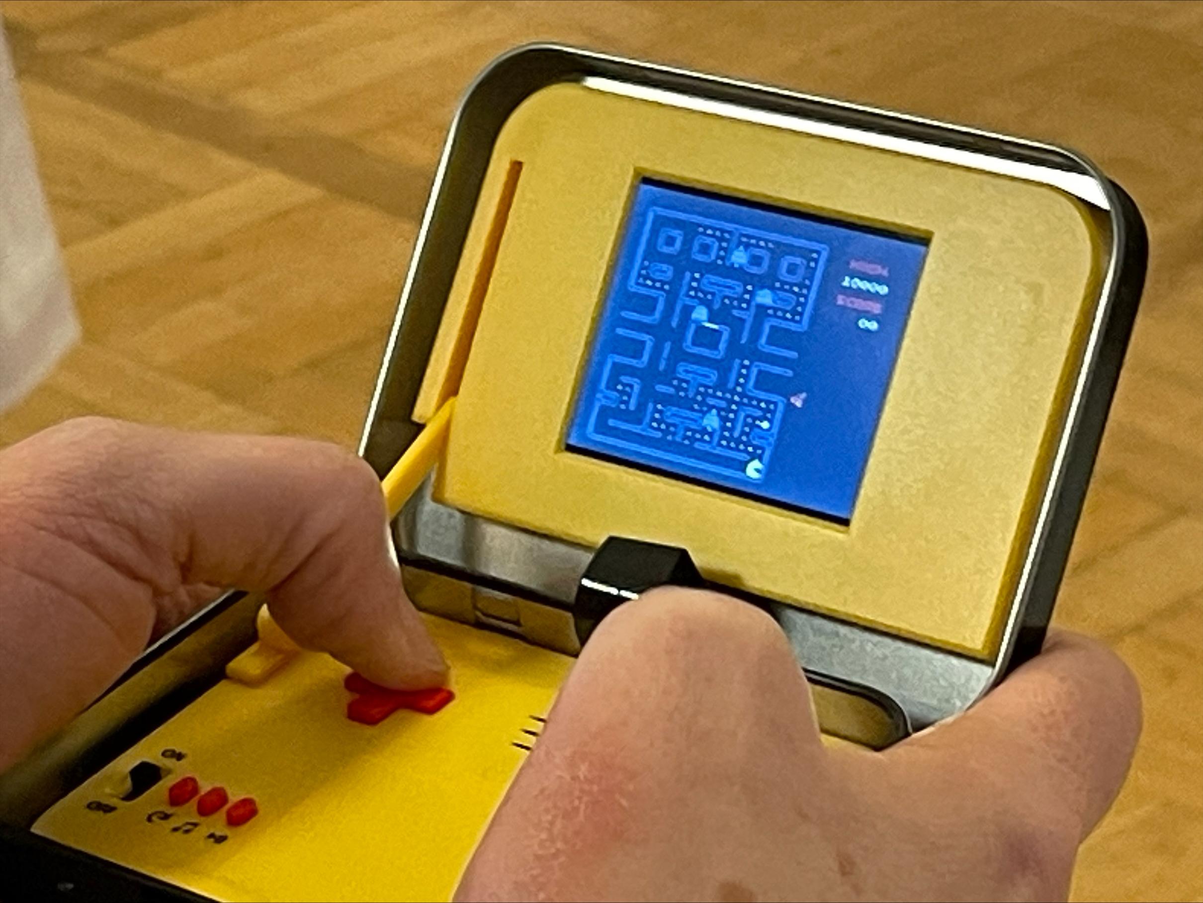 Eine Person spielt Pac-man auf einer Spielekonsole.