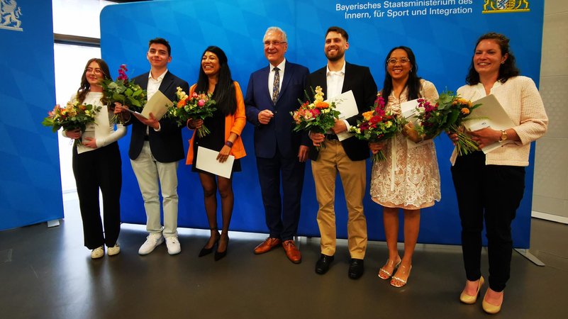 Frauen und Männer mit Blumensträußen und Einbürgerungsurkunden | Bild: BR / Sophia Ruhstorfer Frauen und Männer mit Blumensträußen und Einbürgerungsurkunden