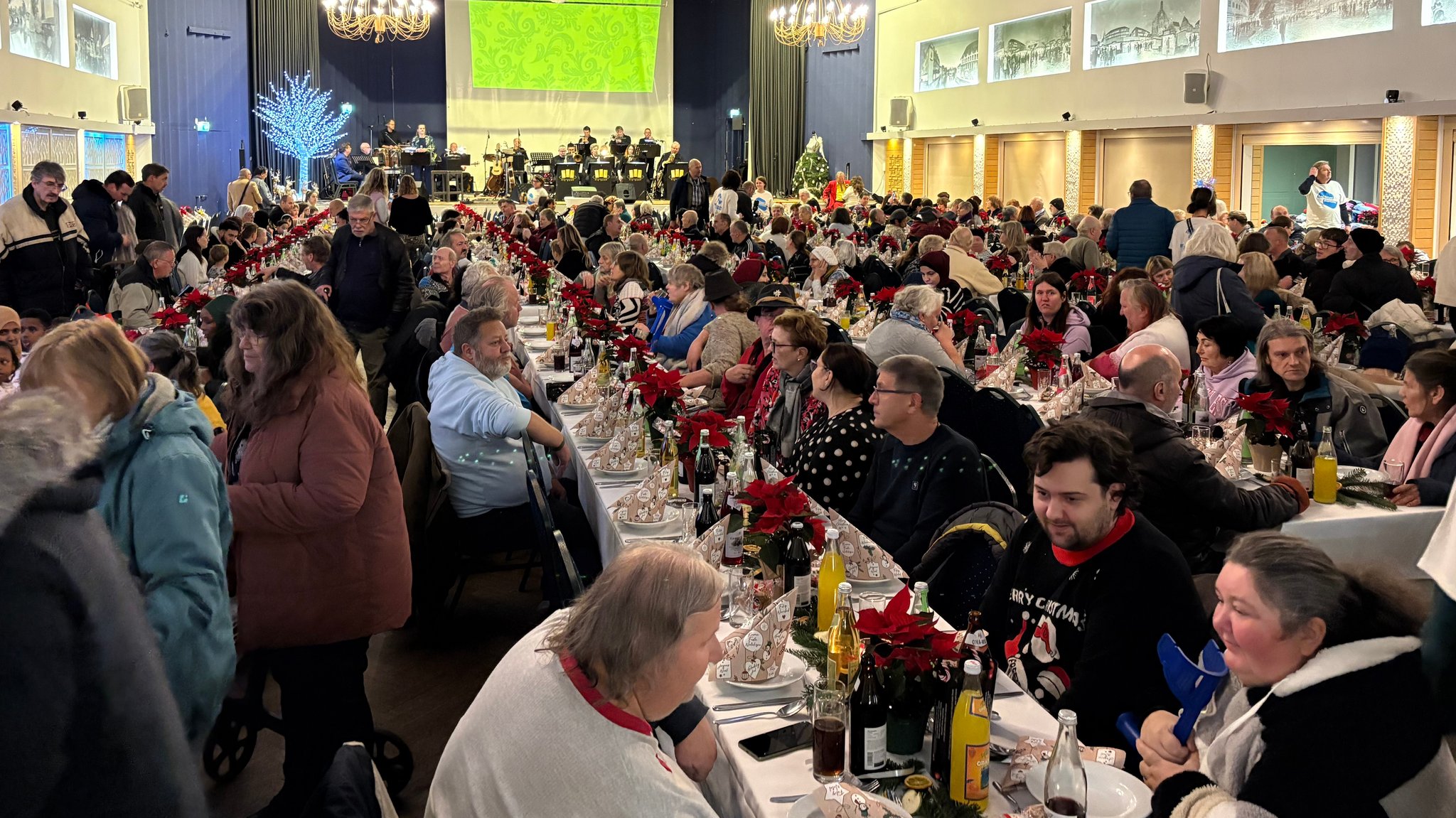 Viele Menschen sitzen an langen Tafeln. Sie alle wurden zu der XXL-Weihnachtsfeier eingeladen