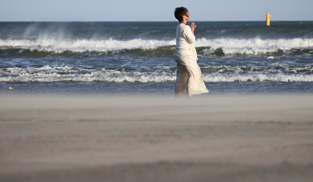 Eine Frau betet an einem Strand bei Fukushima (März 2021)