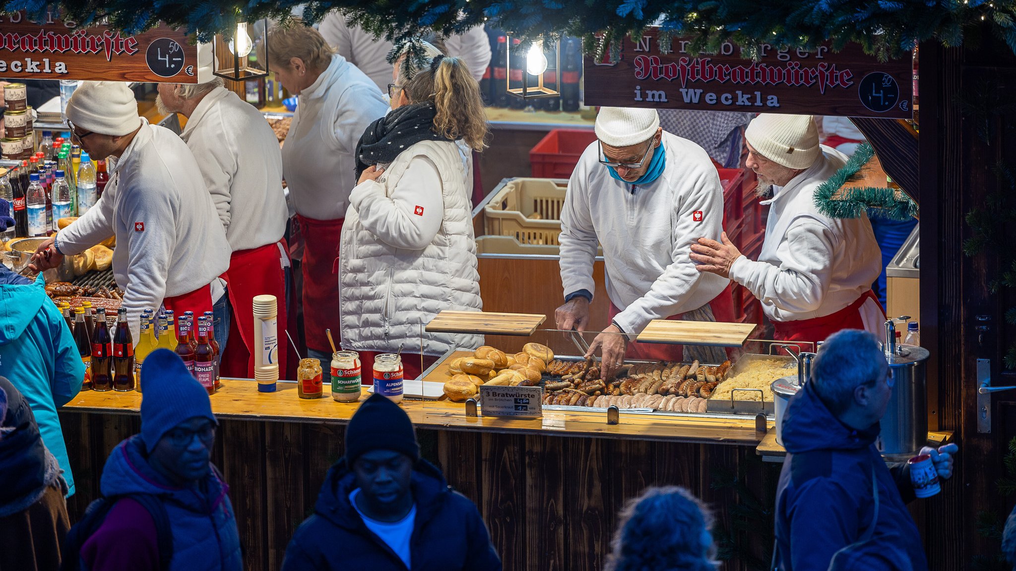 In einem Verkaufsstand bereitet ein Mann Bratwürste zu.