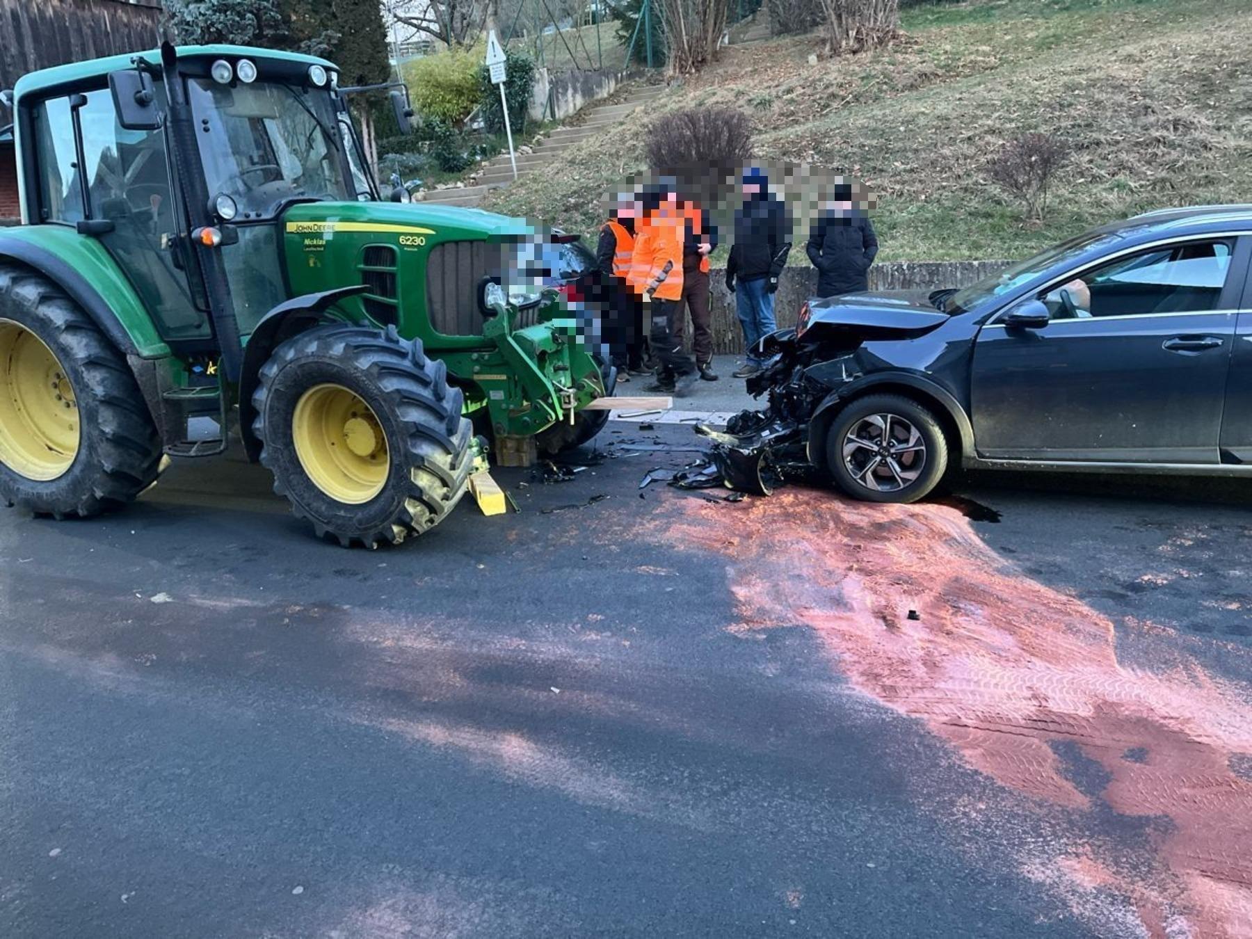 Ein Auto und ein Traktor stehen nach einem Frontalzusammenstoß auf der Straße. 