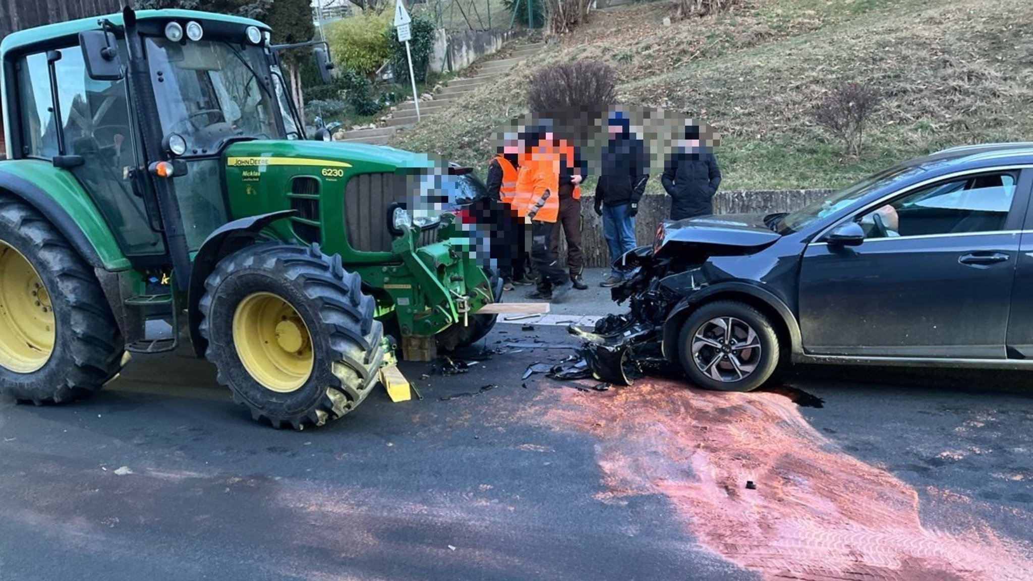 Ein Auto und ein Traktor stehen nach einem Frontalzusammenstoß auf der Straße. 