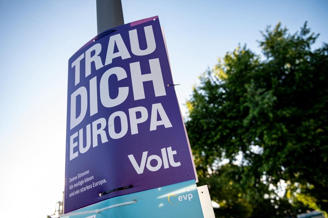 Ein Wahlplakat der Partei "Volt" hängt an einer Straßenlaterne.