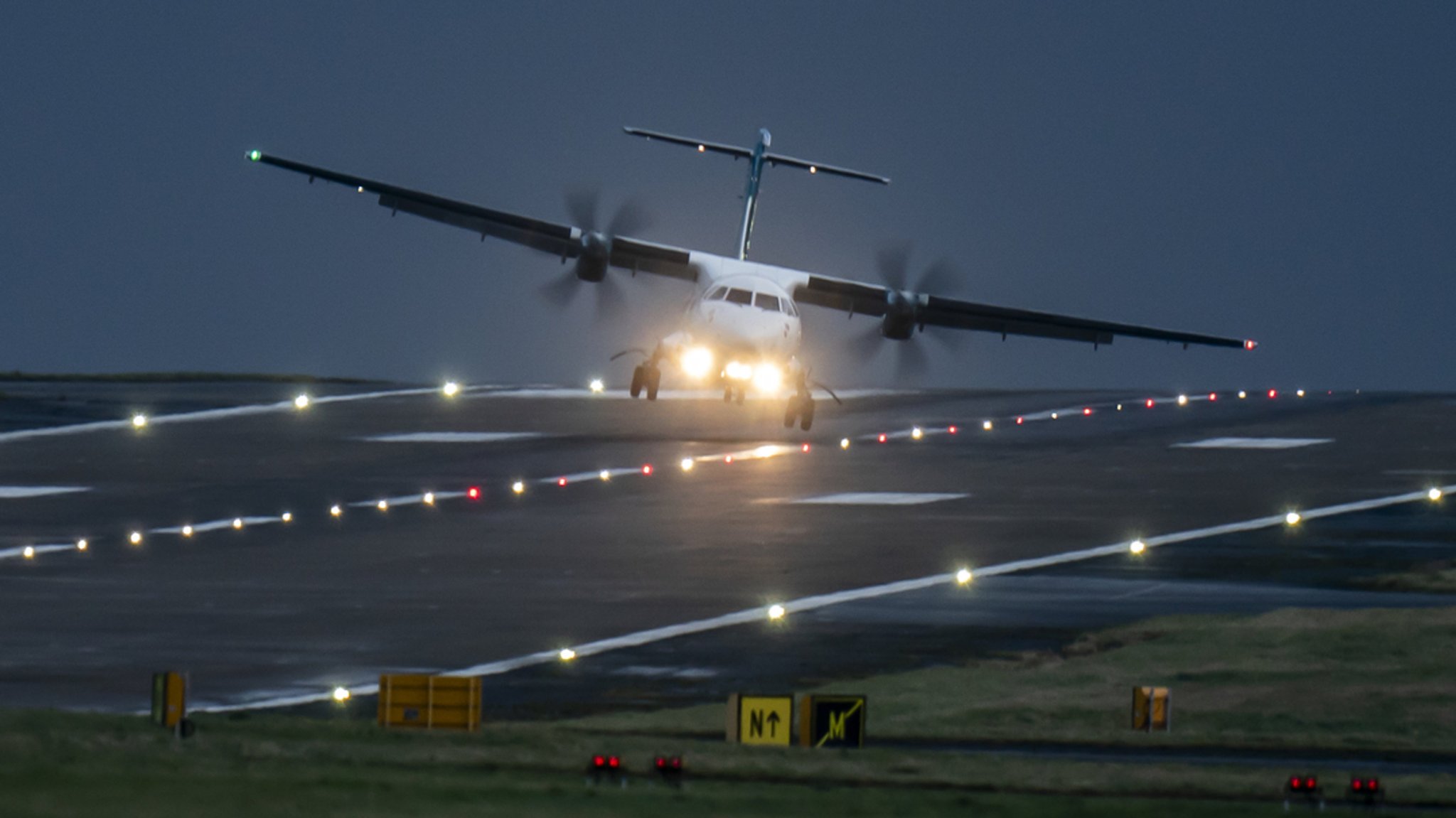 Ein Flugzeug landet bei starkem Wind und hängt schräg knapp über der Landebahn