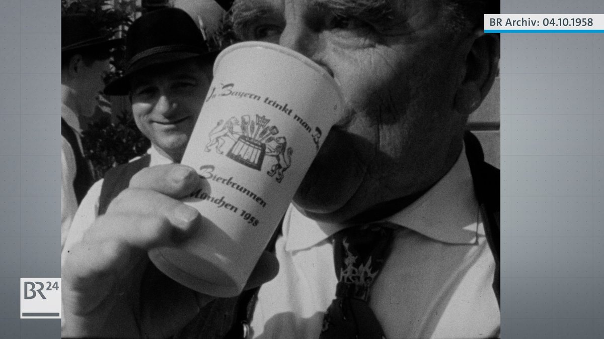 Mann trinkt Bier aus Becher mit der Aufschrift "In Bayern trinkt man Bier - Bierbrunnen München 1958"
