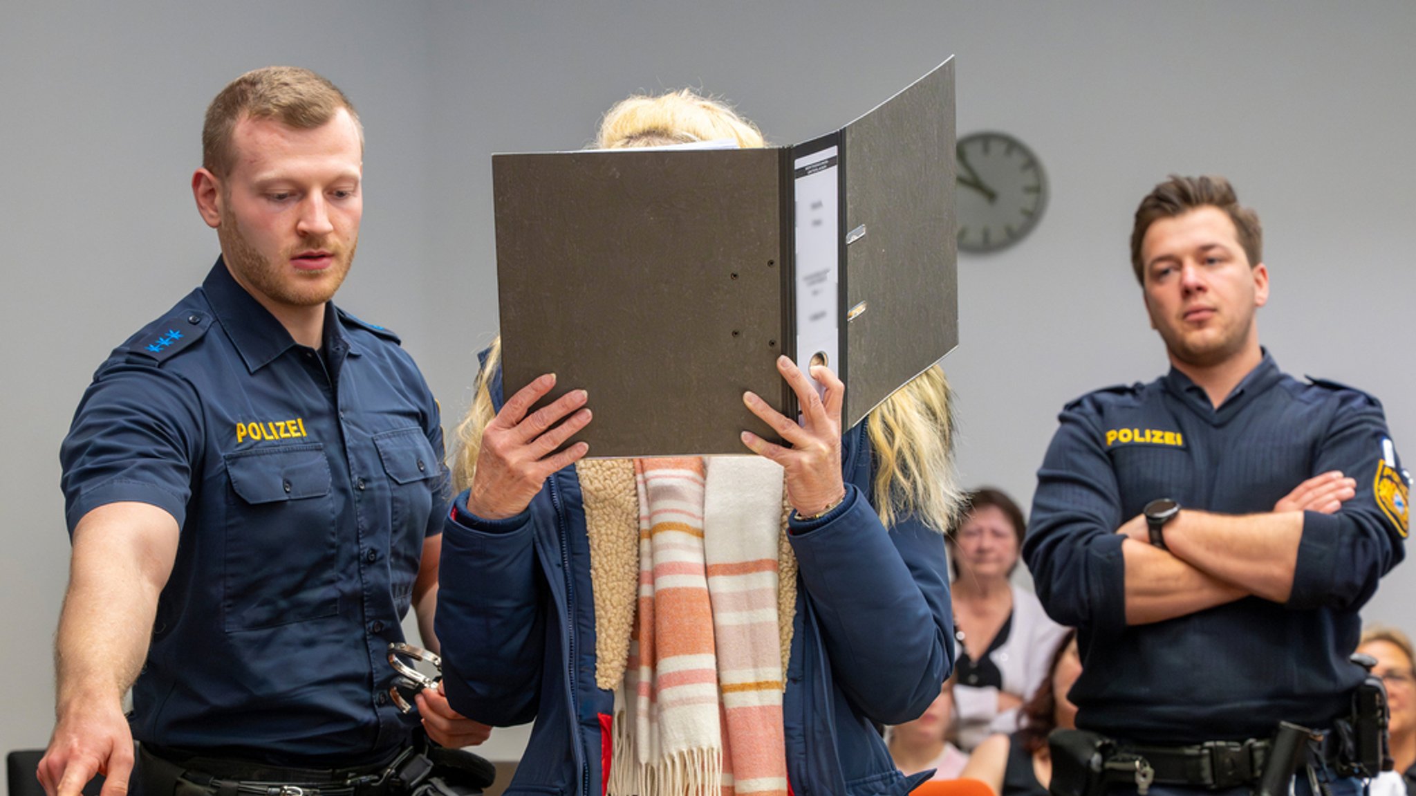 Die Angeklagte Ehefrau vor Gericht. Sie versteckt ihr Gesicht hinter einem Ordner. | Bild: dpa-bildfunk/Peter Kneffel Die Angeklagte Ehefrau vor Gericht. Sie versteckt ihr Gesicht hinter einem Ordner.