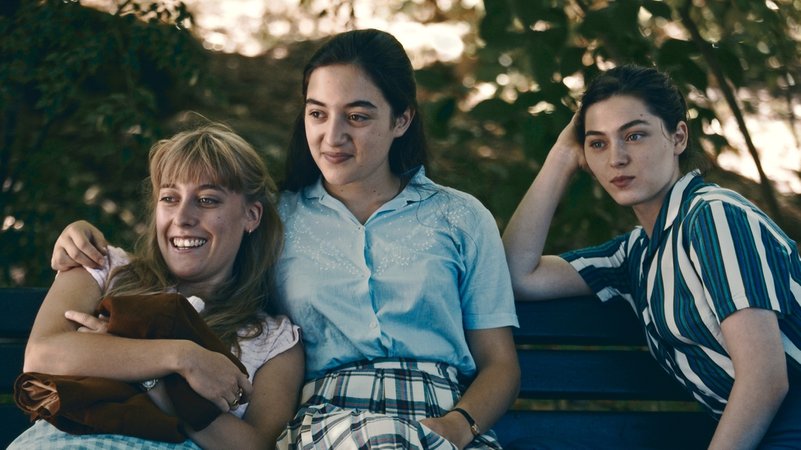 Drei junge Frauen auf einer Parkbank.