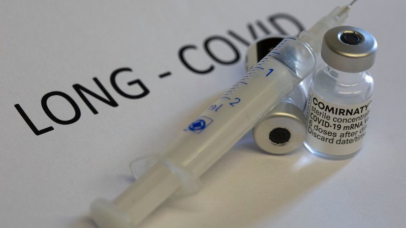 Long-Covid-Schriftzug, daneben eine Impfspritze und Impfstoff