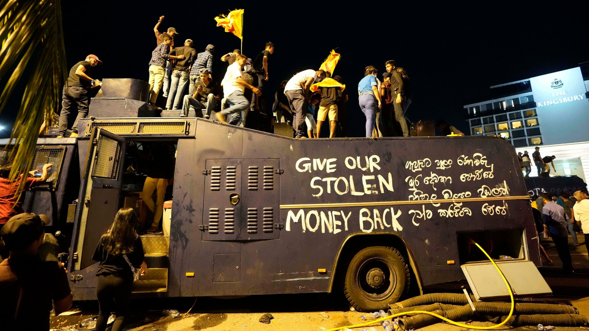 Demonstranten stehen auf einem zerstörten Wasserwerfer der Polizei und rufen Parolen am Eingang der offiziellen Residenz des Präsidenten.