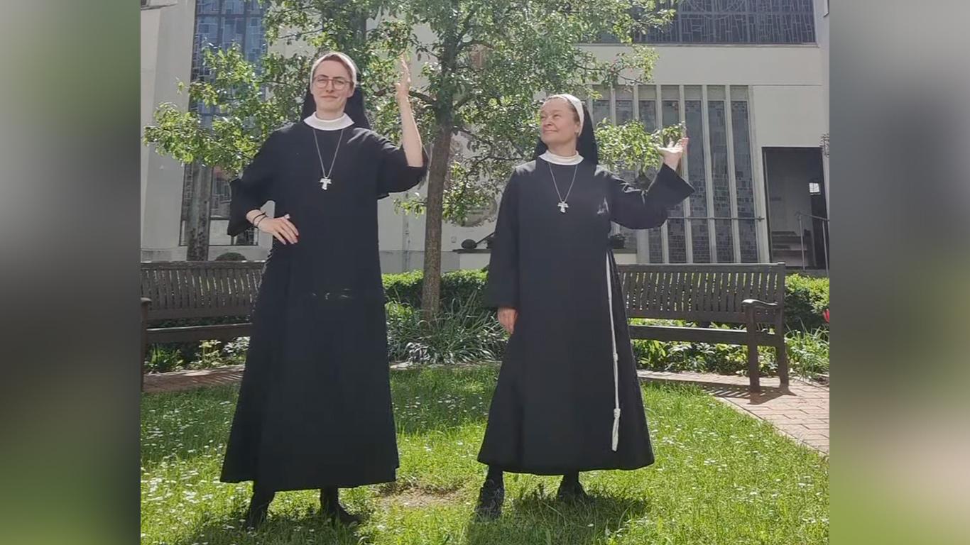 Zwei tanzende Nonnen in einem Klostergarten.
