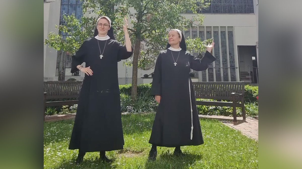 Zwei tanzende Nonnen in einem Klostergarten.