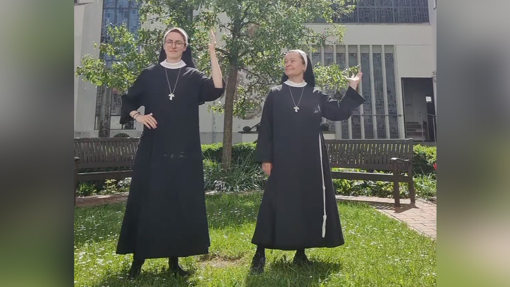 Zwei tanzende Nonnen in einem Klostergarten.