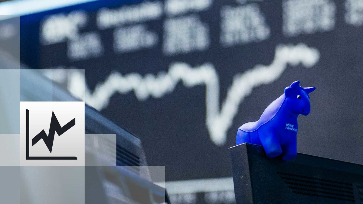 in blauer Stier aus Gummi sitzt auf der oberen Kante eines Bildschirmes, im Hintergrund die Kurstafel der Börse