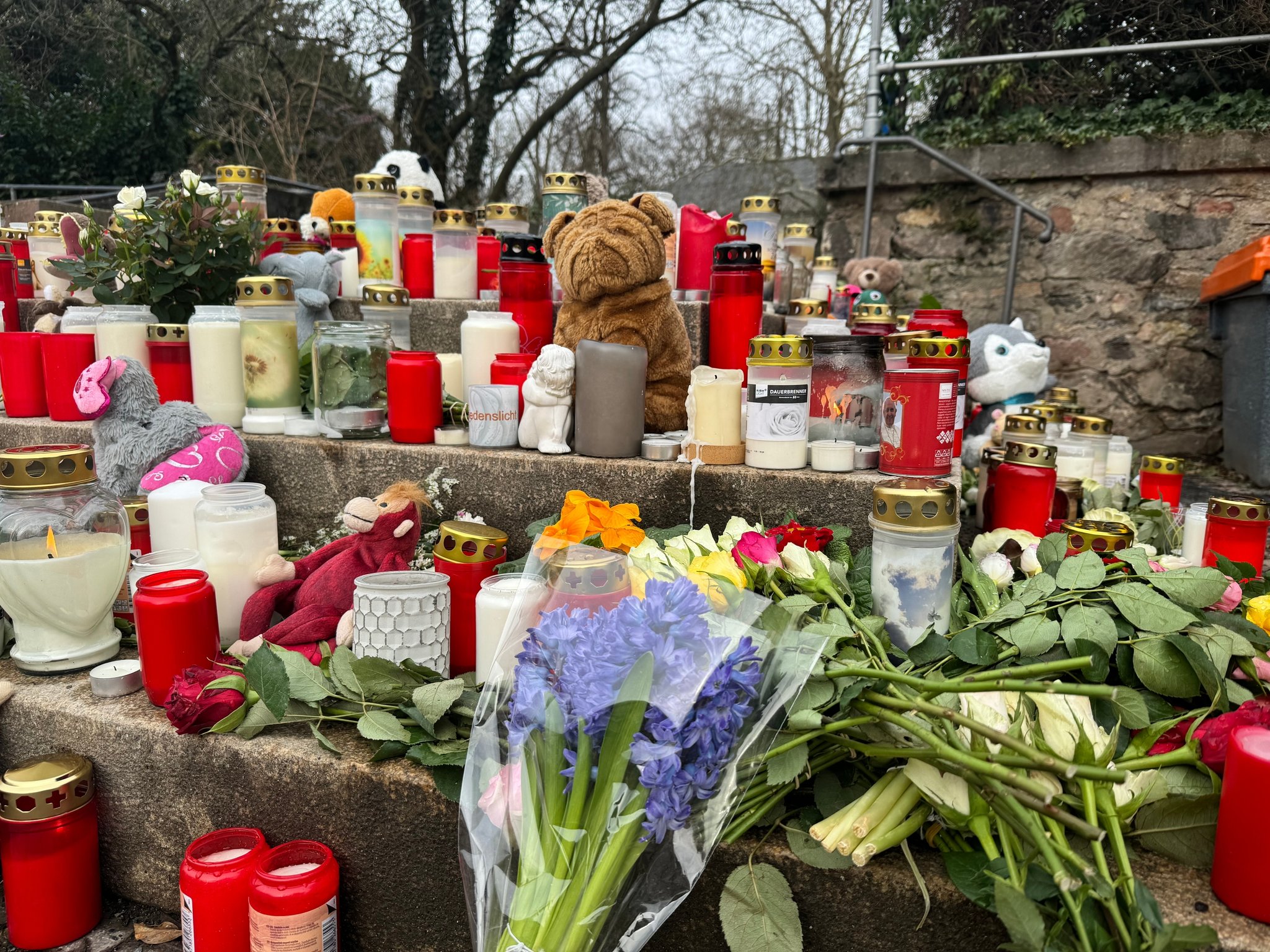 24.01.2025, Aschaffenburg - Zwei Tage nach dem Messerangriff liegen Blumen, Kerzen und Stofftiere in der Nähe des Tatorts.