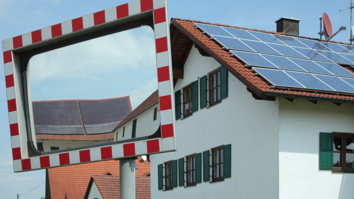 Solarzellen auf zwei Hausdächern, von denen eines in einem Verkehrsspiegel sichtbar ist