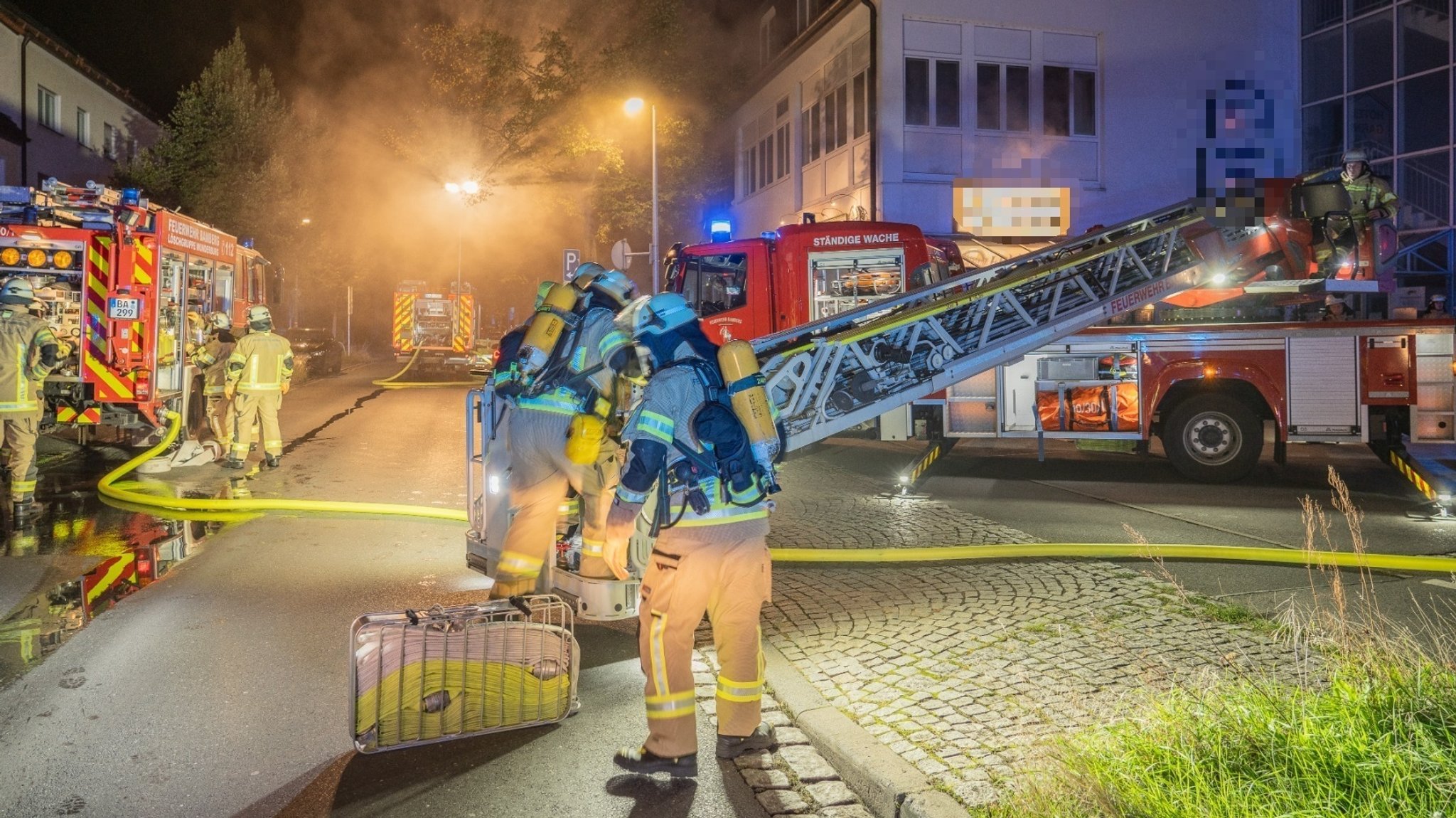 Feuerwehrleute stehen vor einem Hotel in Bamberg Die Straße ist verraucht. 