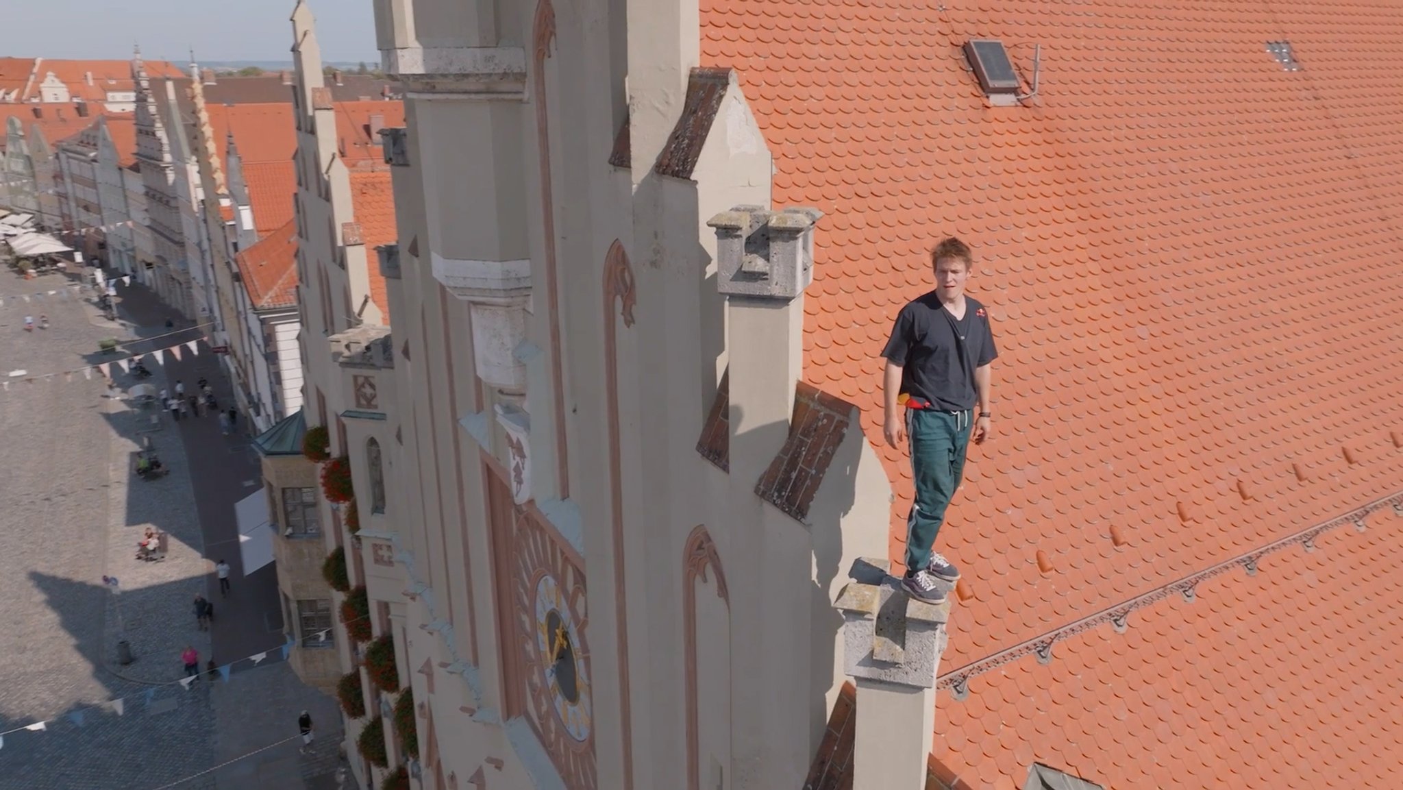 Ein Mann steht hoch oben auf dem Giebel eines Hauses in der Landshuter Altstadt. 