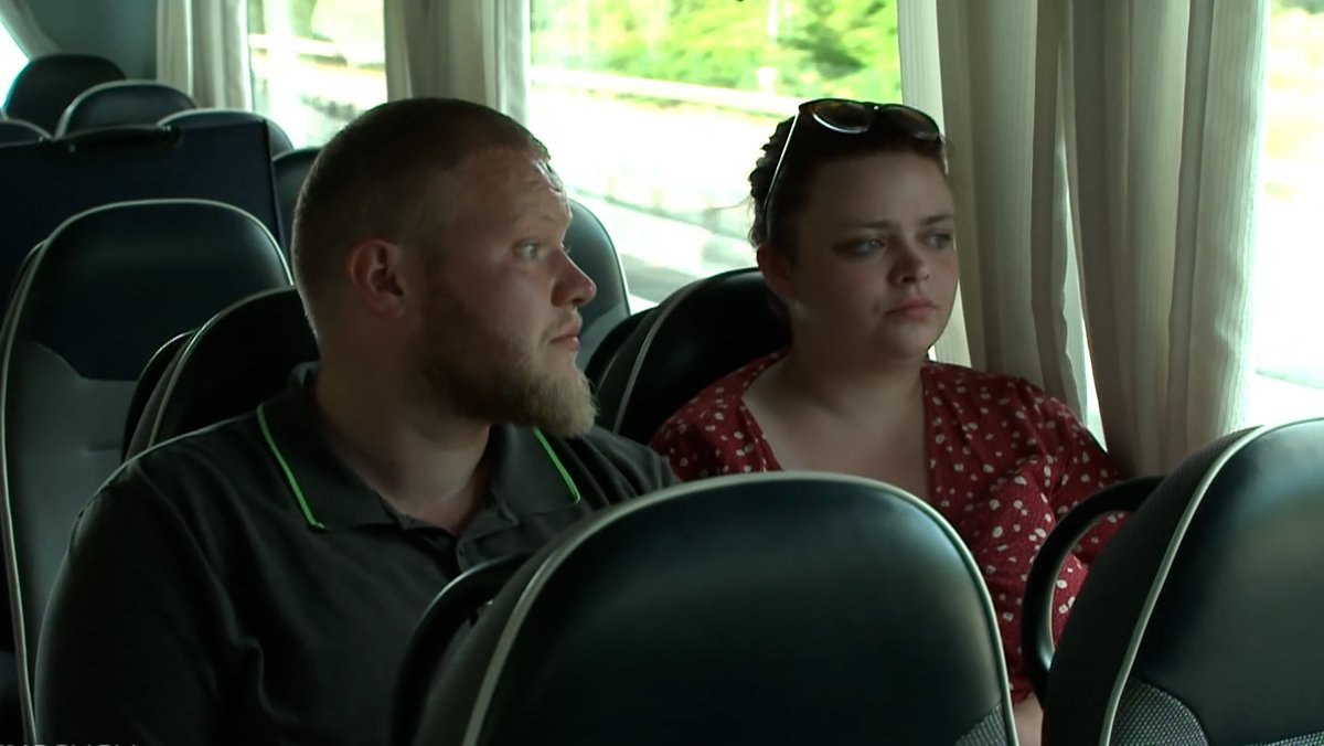 Zwei junge Erwachsene sitzen in einem Bus. 