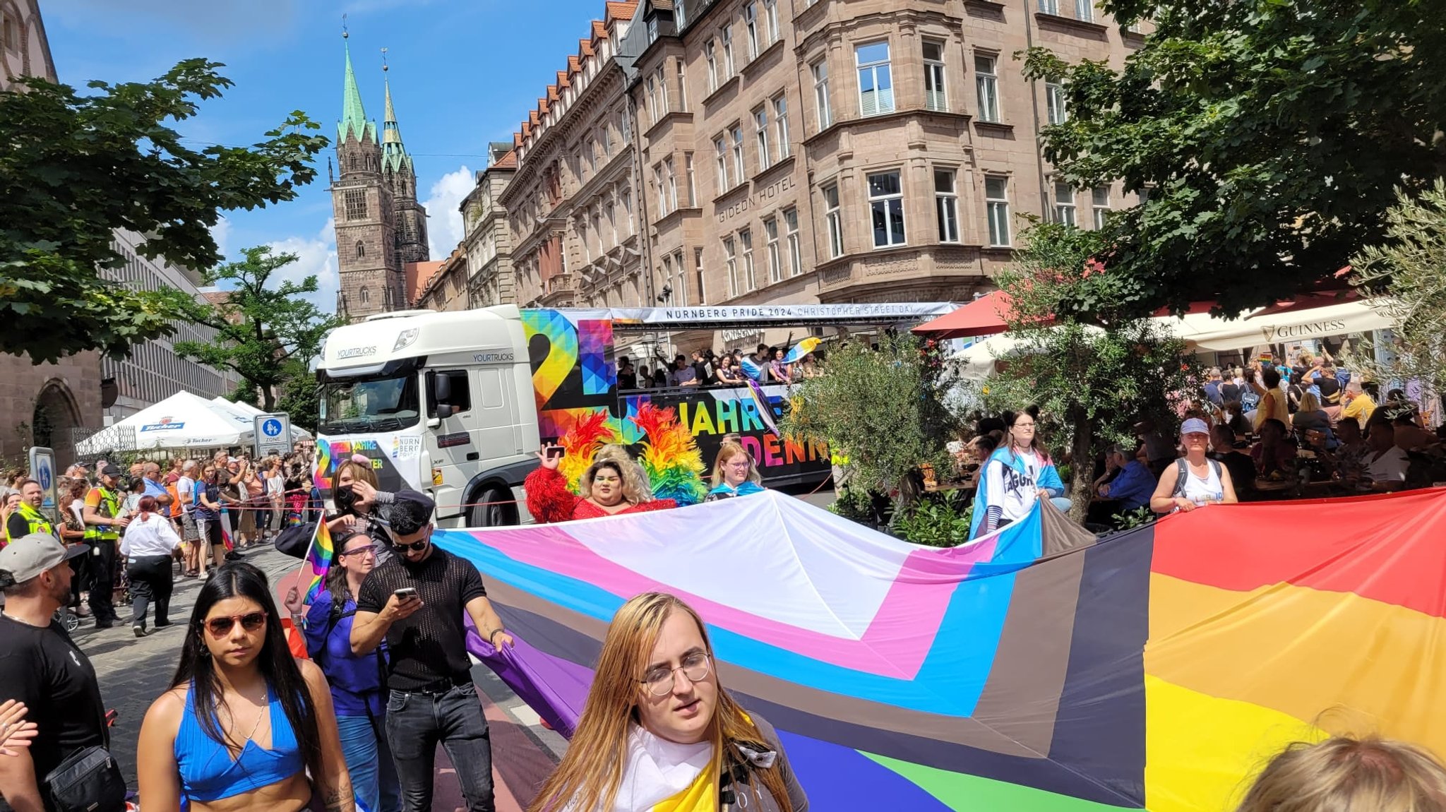 Menschen tragen beim CSD Nürnberg eine bunte Flagge durch die Straße.